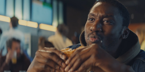 A man eating a Burger King whopper in a restaurant